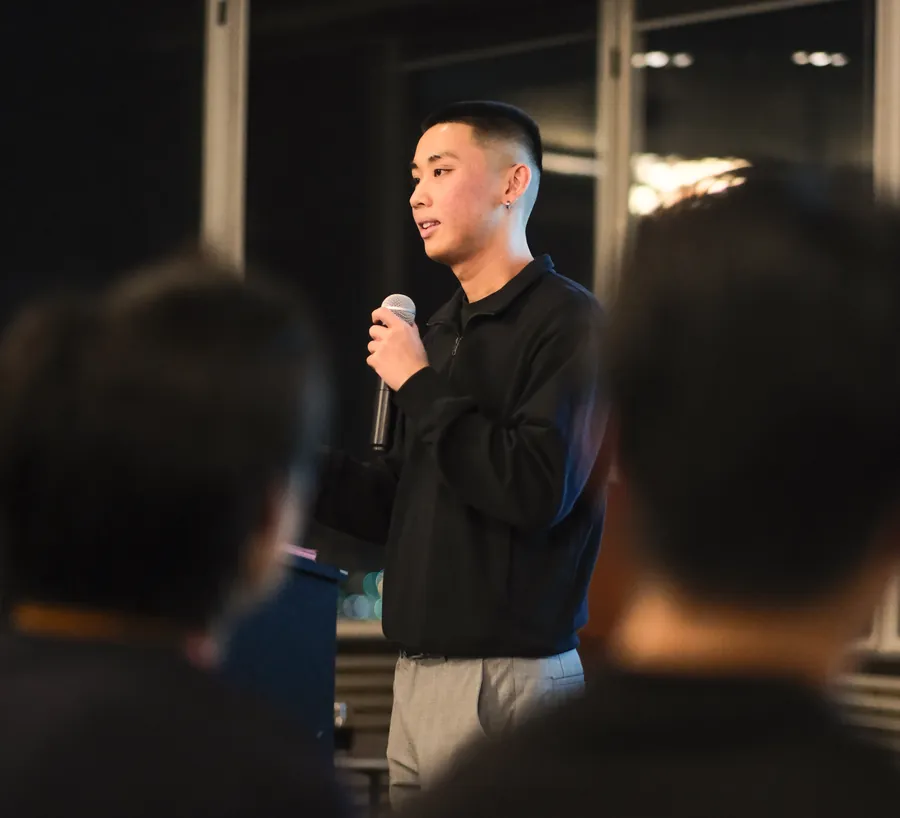 Jordan Pham speaking to members with a microphone