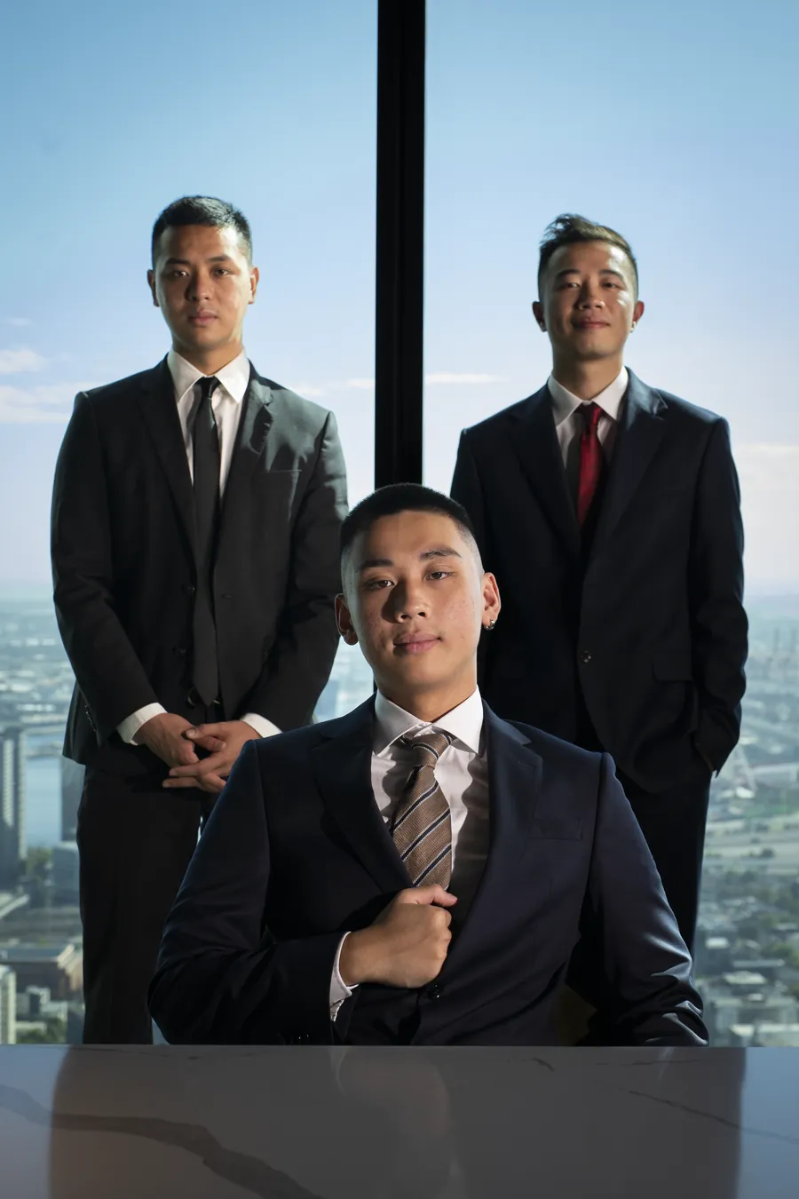 Stanley Ma, Jordan Pham and Terence Mok at a high-rise window over Melbourne