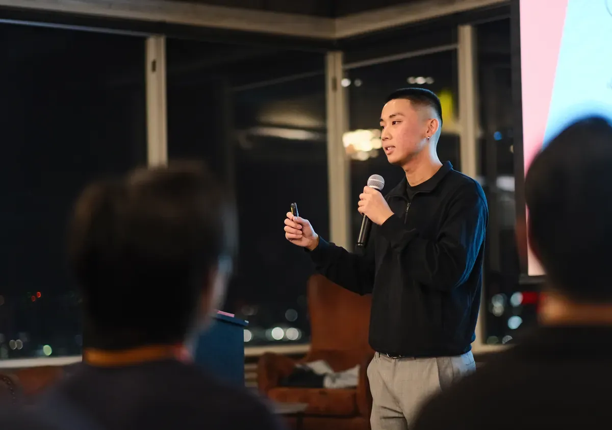 Jordan Pham speaking to a room of members at night